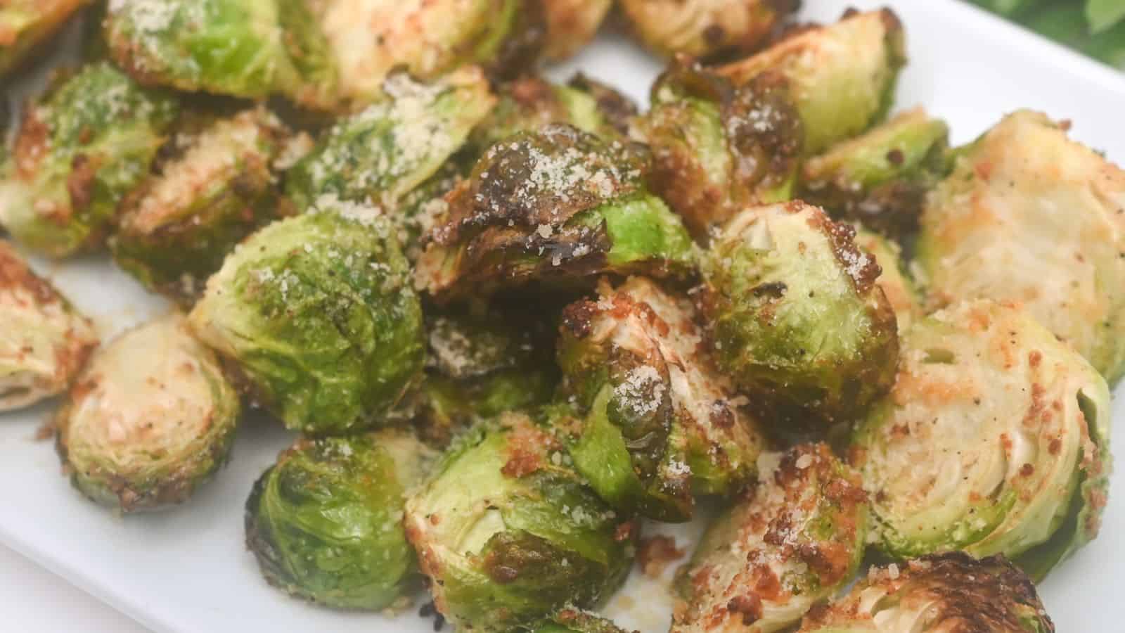 Air-fried brussels sprouts with grated parmesan cheese on a white plate.