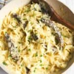 Alfredo steak pasta in skillet with wooden spoon.