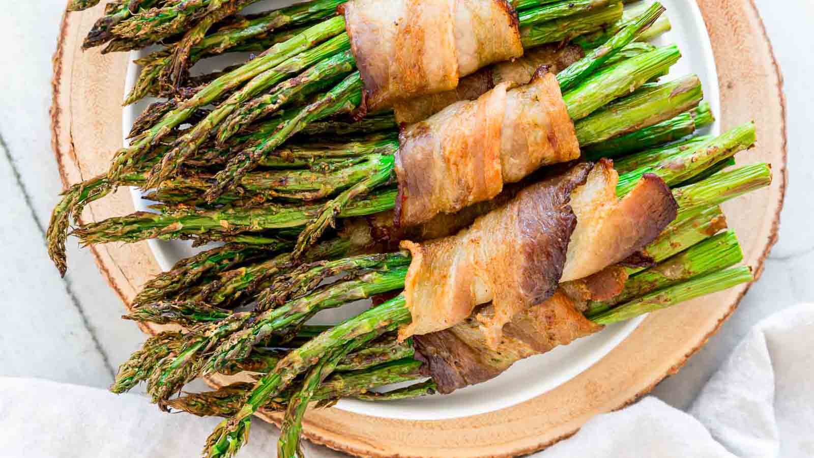 https://tastesdelicious.com/wp-content/uploads/2024/04/bacon-wrapped-asparagus-msn-1.jpg