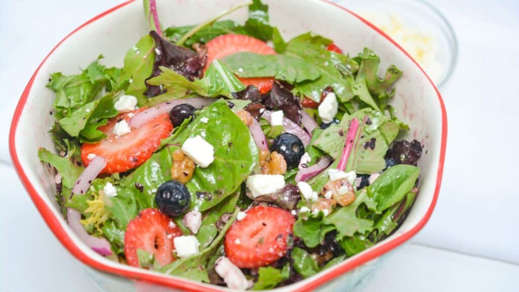 A salad with strawberries, blueberries and feta cheese.