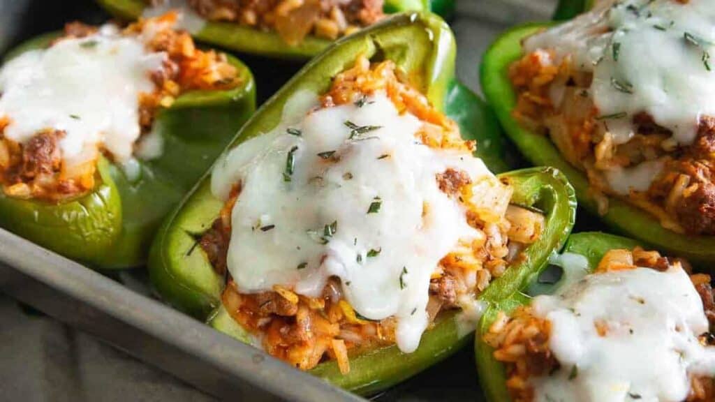 Stuffed bell peppers with melted cheese on a baking tray.