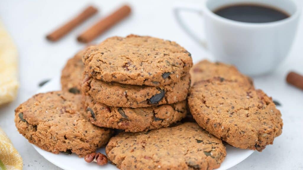 Seed and nut butter cookies on plate served with coffee.