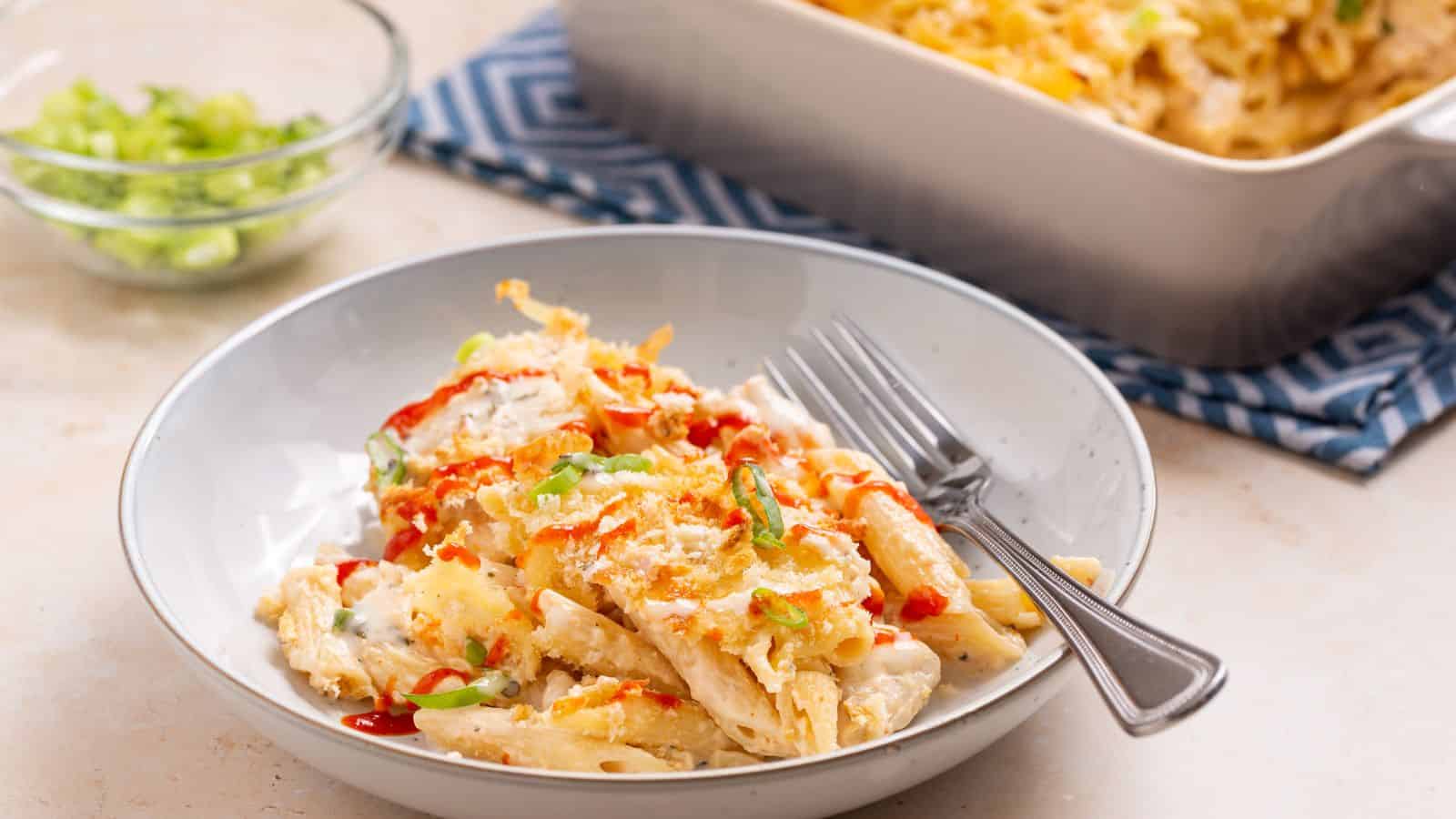 Serving of buffalo chicken pasta bake with casserole dish.