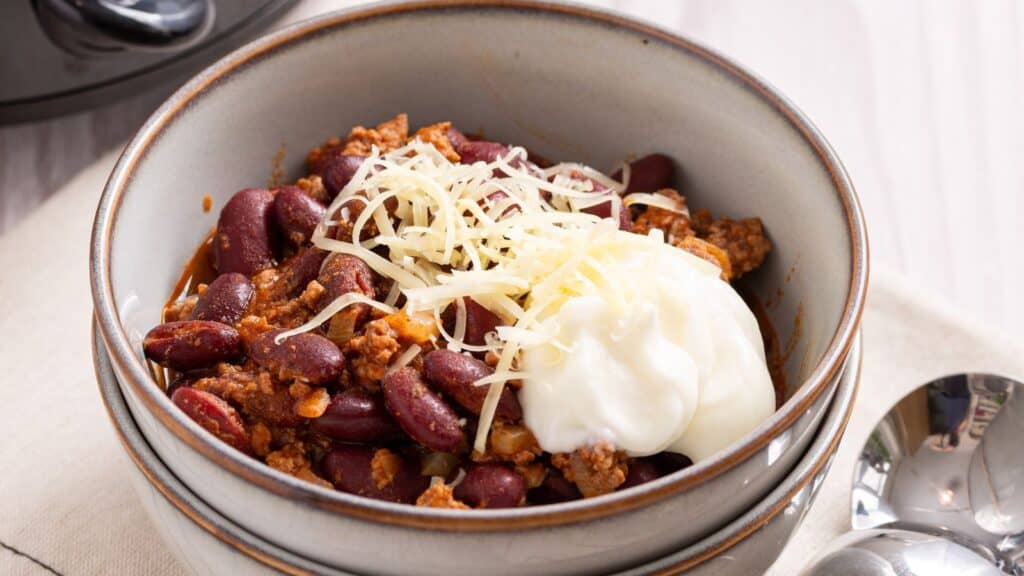 Bowl of chili topped with shredded cheese and a dollop of sour cream.