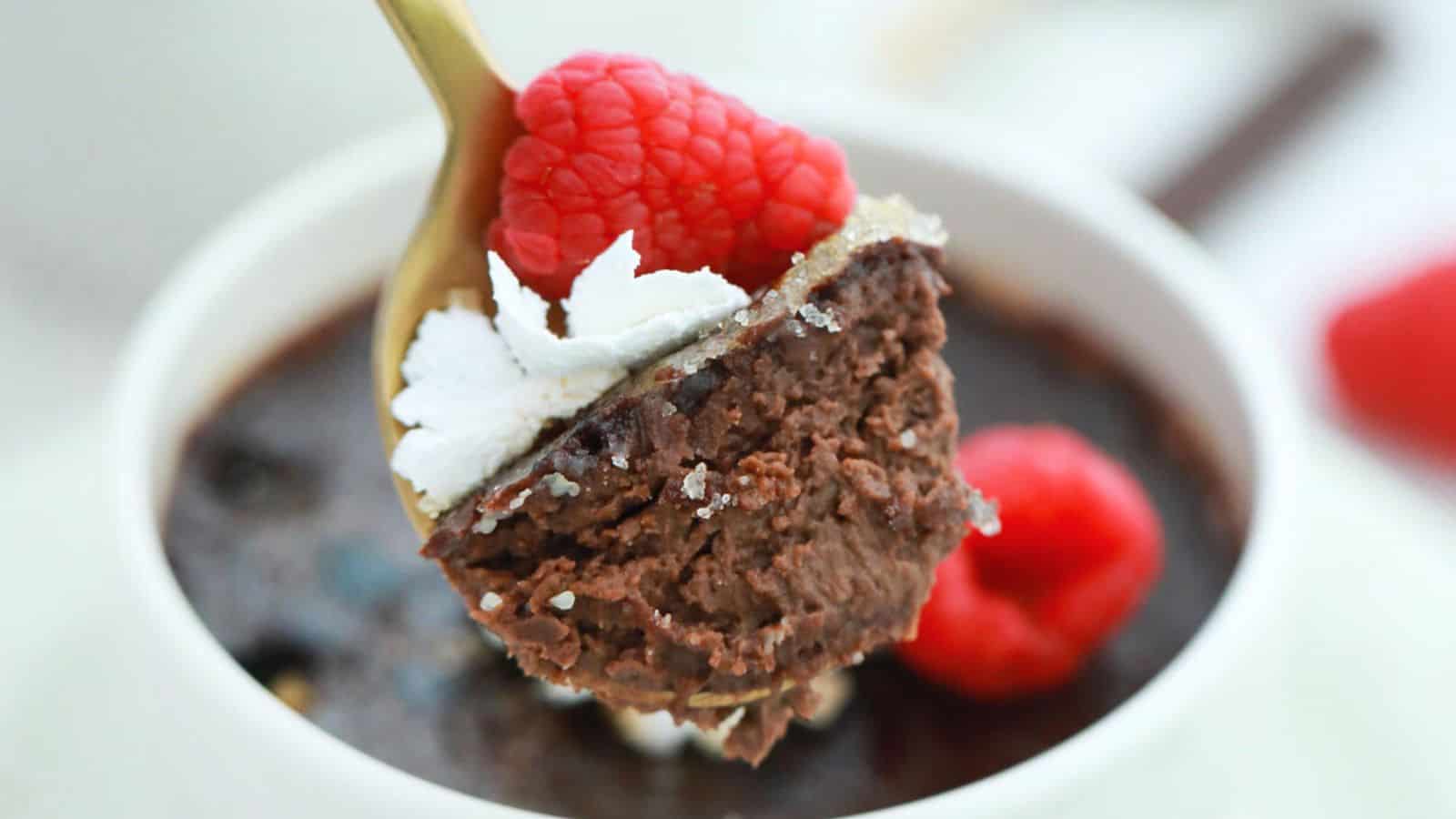 Three cups of chocolate pudding with whipped cream and raspberries.