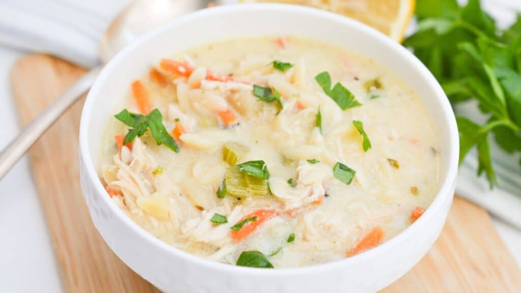 A bowl of creamy chicken and vegetable soup garnished with fresh herbs.