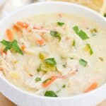 A bowl of creamy chicken and vegetable soup garnished with fresh herbs.