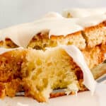 A close-up of a frosted cake with a fork lifting a bite, displaying a fluffy texture and creamy icing.