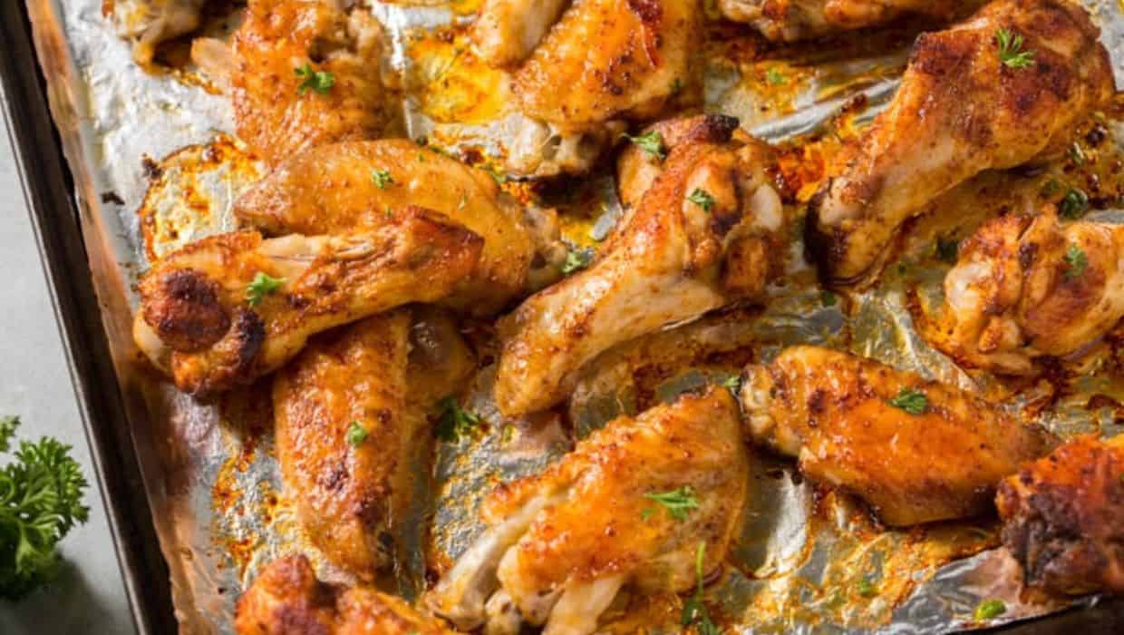 Golden-brown roasted chicken drumsticks on a baking sheet, garnished with fresh parsley.