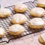Lemon ricotta cookies on rack with icing bowl.