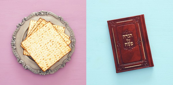 A plate of matzo on a pastel background adjacent to a haggadah, the jewish text read during passover.