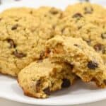 A plate of cookies on a white surface with front one broken in half.