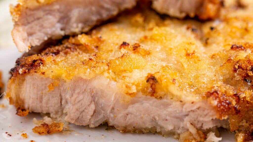 Close-up of a crispy breaded pork cutlet sliced open to reveal its tender interior.