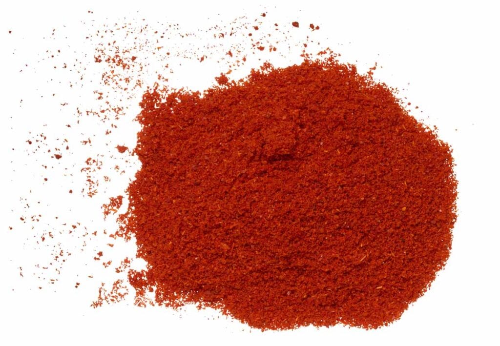 A pile of bright red paprika scattered loosely against a white background.
