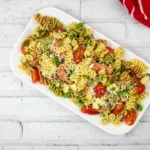 A platter of pizza pasta salad served on a white rectangular dish.