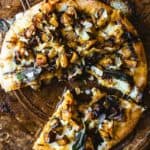 Gourmet pizza with mushrooms, caramelized onions, and melted cheese on a rustic wooden table.