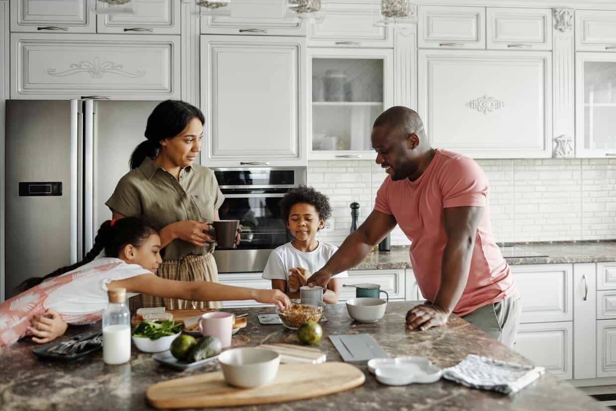 A family with two kids and their parents preparing breakfast together in a modern kitchen.