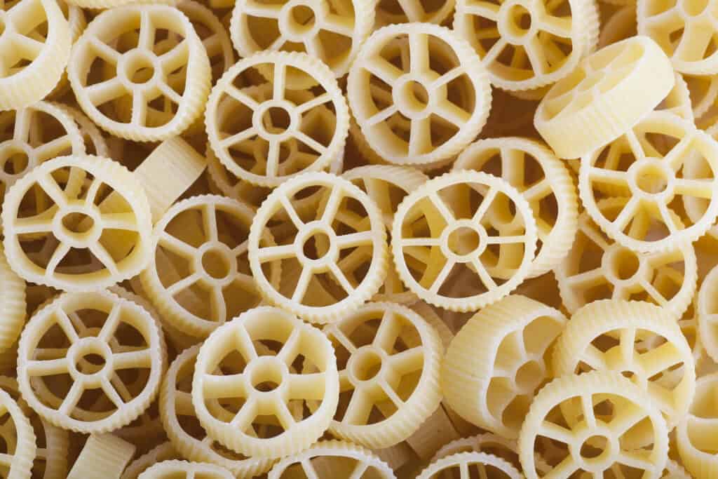 Close-up view of wheel-shaped pasta noodles, known as "rotelle," displayed in bulk with a focus on their detailed texture.
