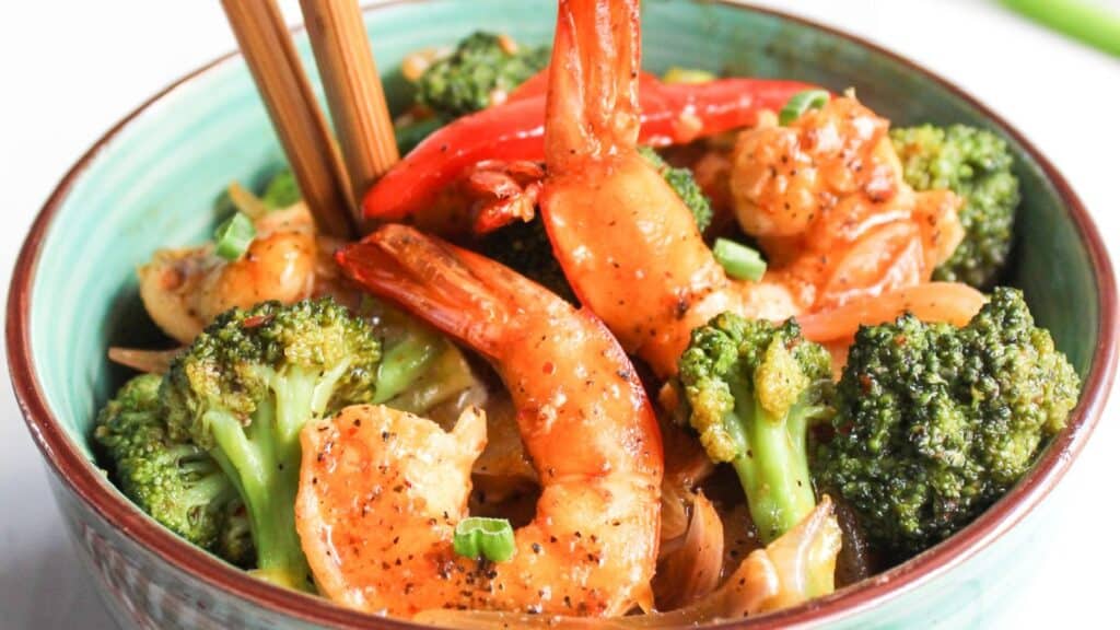 Shrimp and broccoli stir-fry served in a bowl with chopsticks.