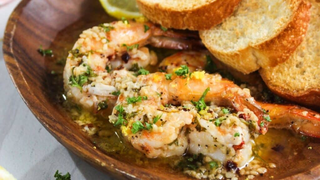 Sautéed shrimp in garlic butter sauce served with slices of toasted bread.