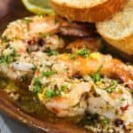 Sautéed shrimp in garlic butter sauce served with slices of toasted bread.