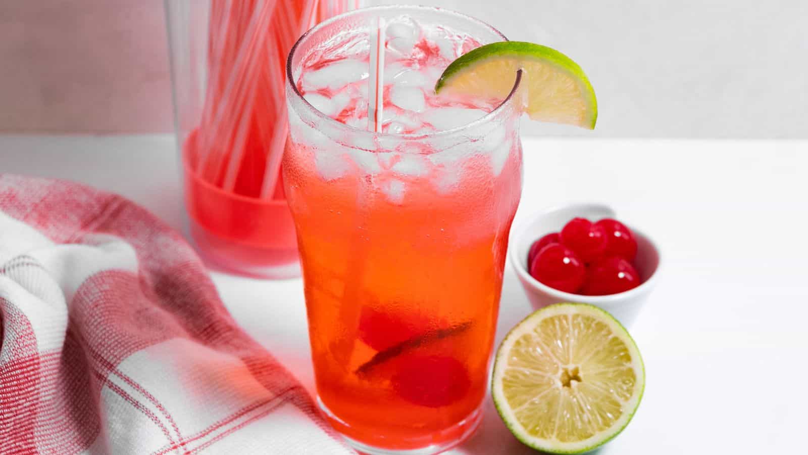 Cherry limeade in tall glass with lime wedge garnish.