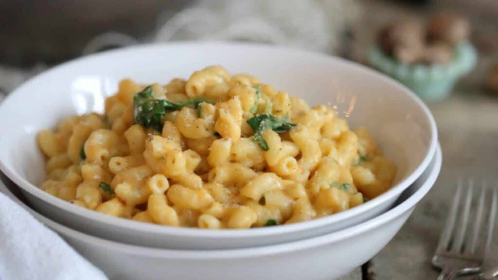Bowl of creamy macaroni and cheese garnished with greens.