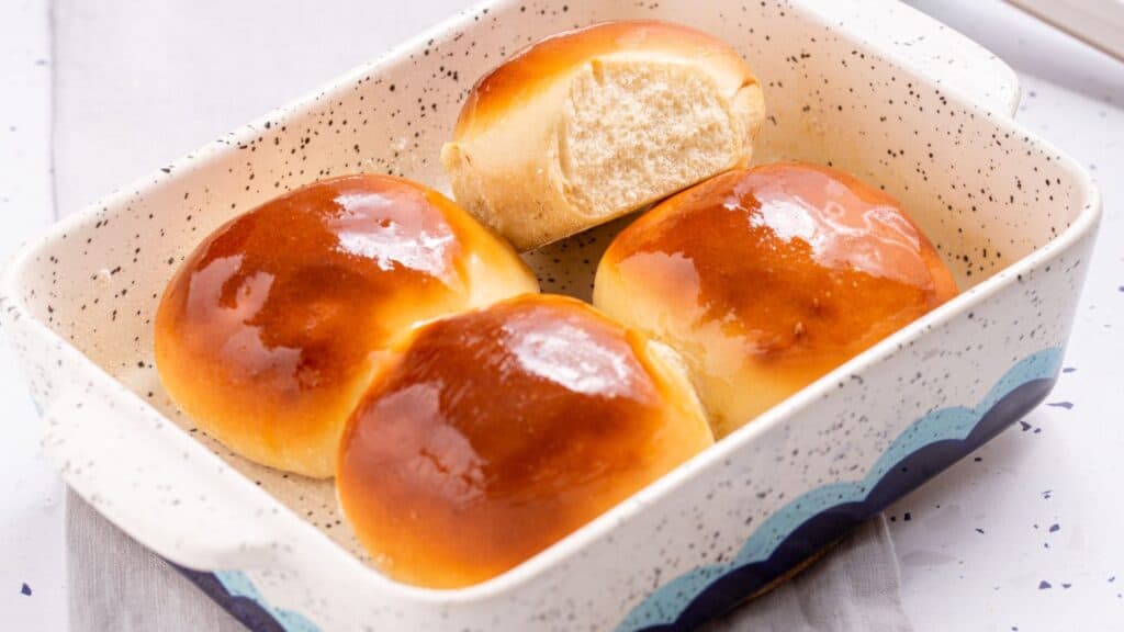 Glazed buns in a ceramic baking dish.