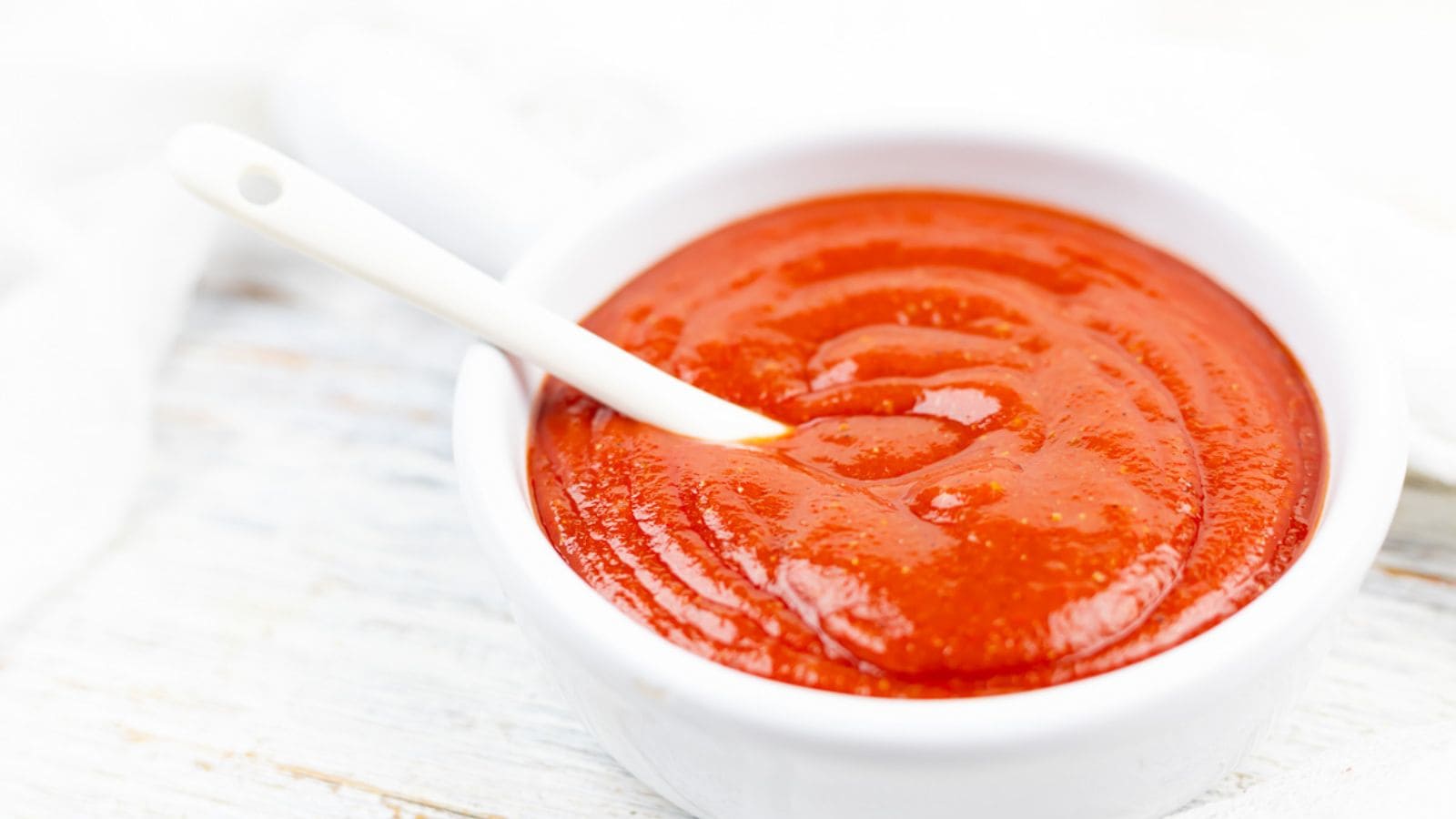 BBQ sauce in a white bowl with a spoon.
