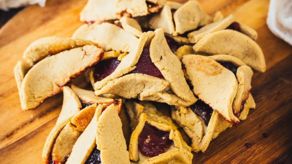 A pile of folded baked goods with visible fruit filling on a wooden surface.