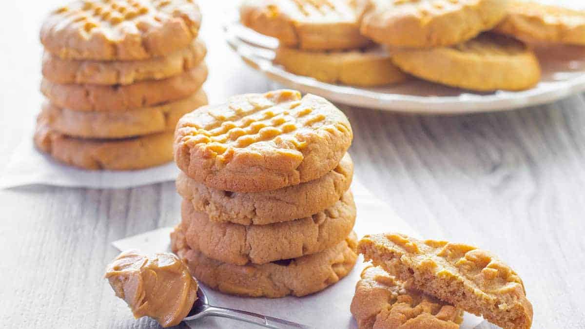 A stack of Classic Peanut Butter Cookies with a spoonful of peanut butter next to it.