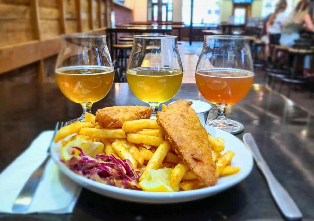 A plate of fish and chips with a flight of beer.