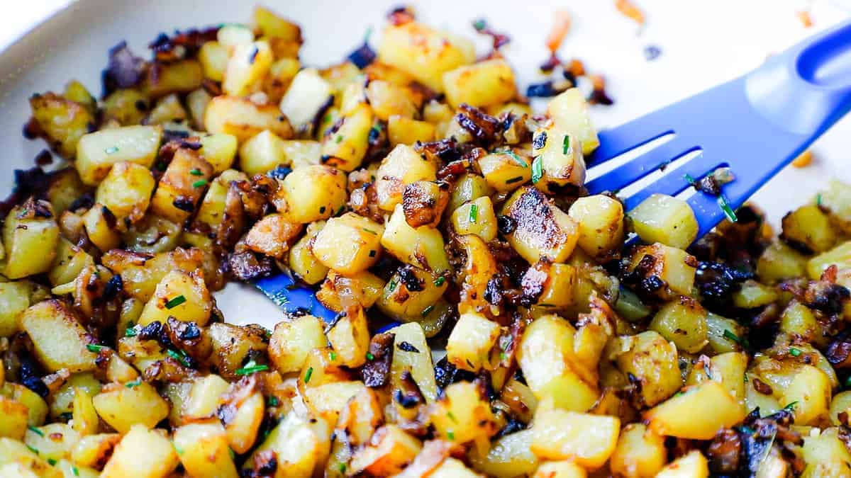 A close up image of Fried Potatoes and Onions in a skillet.