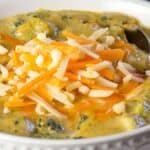 A bowl of low-carb broccoli cheese soup served with a spoon on the side.