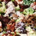 A close-up of a broccoli salad with bacon, sunflower seeds, and a creamy dressing.