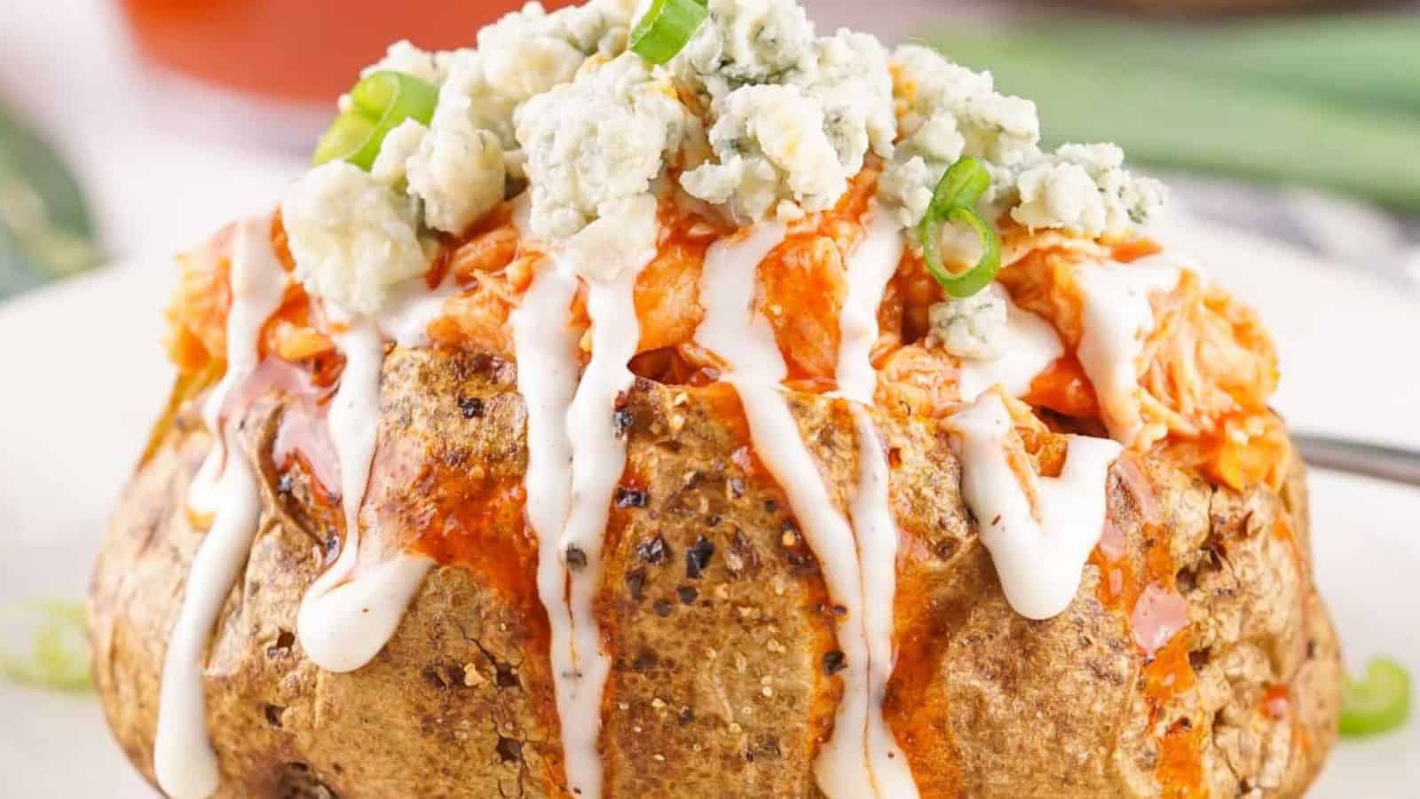 Buffalo Chicken Baked Potatoes topped with blue cheese, drizzled with ranch dressing, and garnished with green onions.