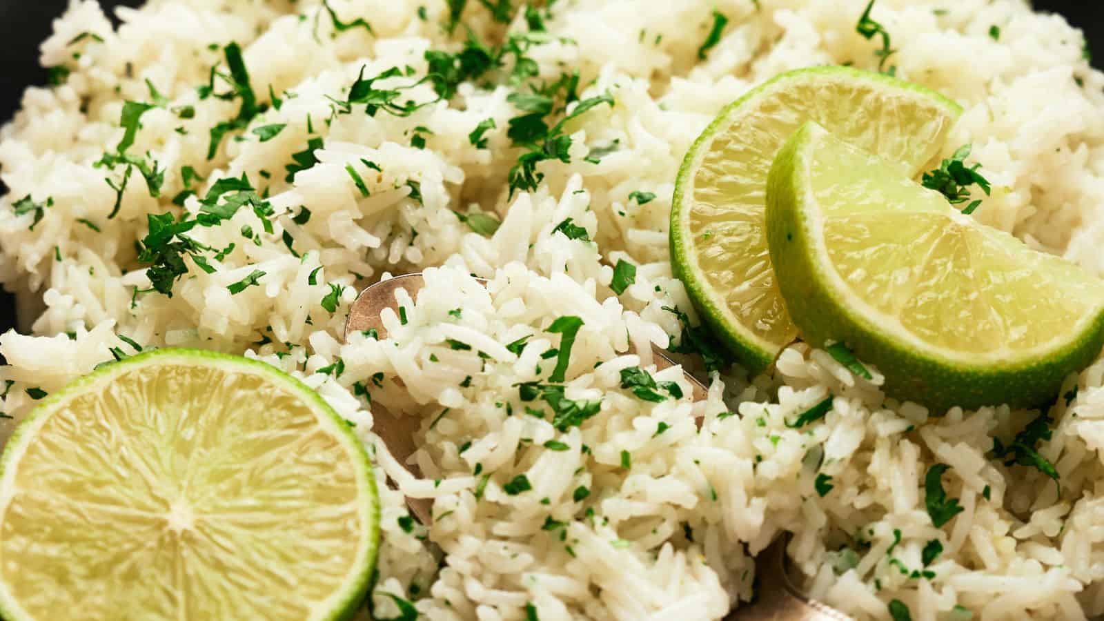 Close-up of a plate of rice garnished with chopped herbs and slices of lime.