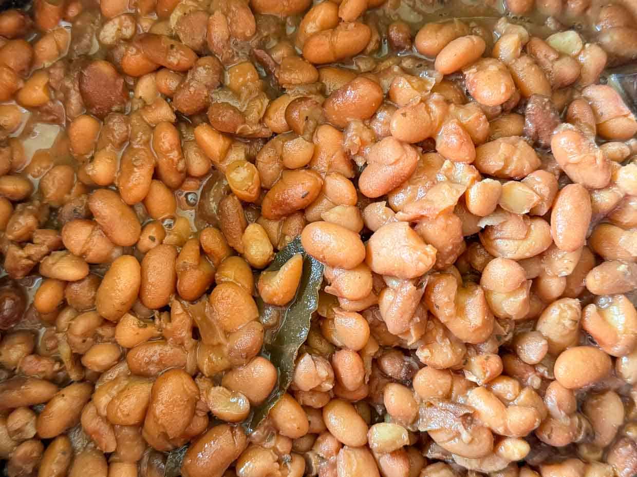 A crock pot full of cooked pinto beans.