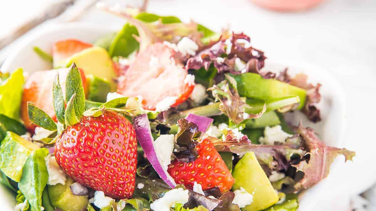 A close up image of a Strawberry Salad with greens, feta cheese and fresh strawberries.