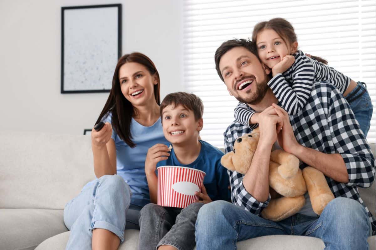 Family happily watching a movie in their home.