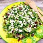 Mediterranean Chopped Salad with crumbled feta cheese, on a yellow plate with flower designs.