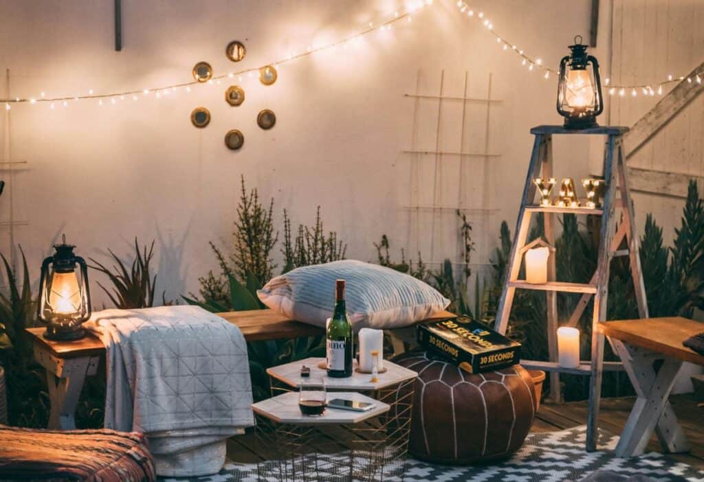 An outdoor seating area with warm lighting, board games and wine.