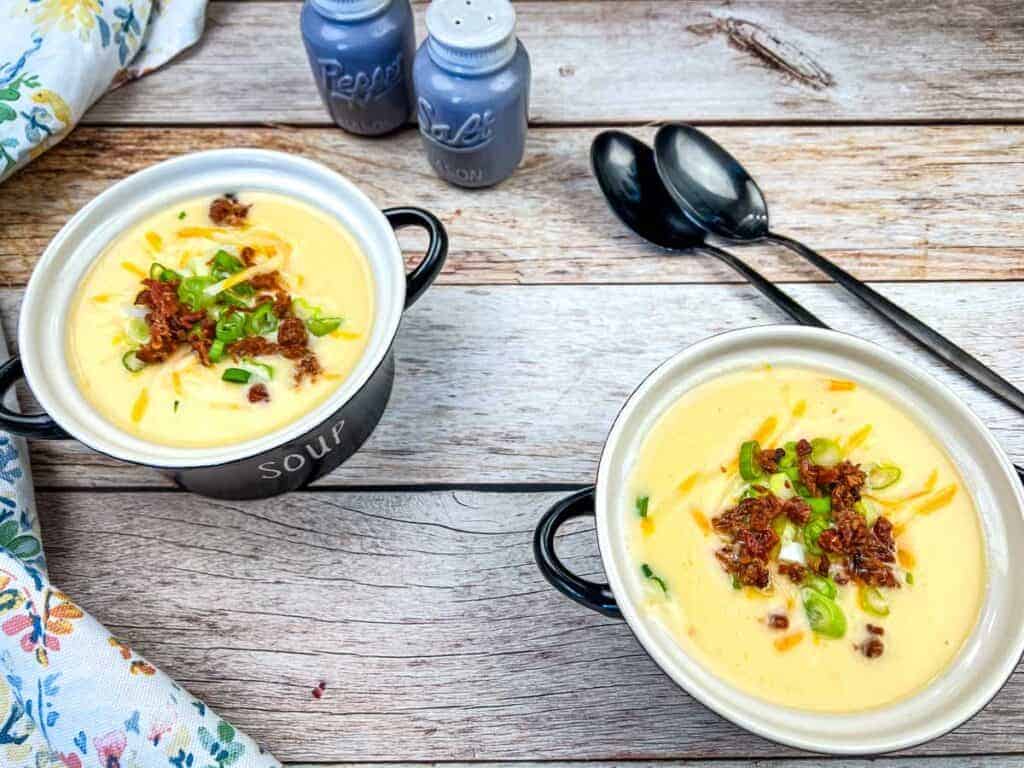 Two bowls of Copycat Jason's Deli Irish Potato Soup on a wooden table.