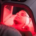 Woman wearing protective eyewear while receiving facial treatment with red light therapy, seeking to understand what is red light therapy.