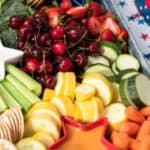 A tray with an assortment of fresh fruits and vegetables and star-shaped dipping bowls.
