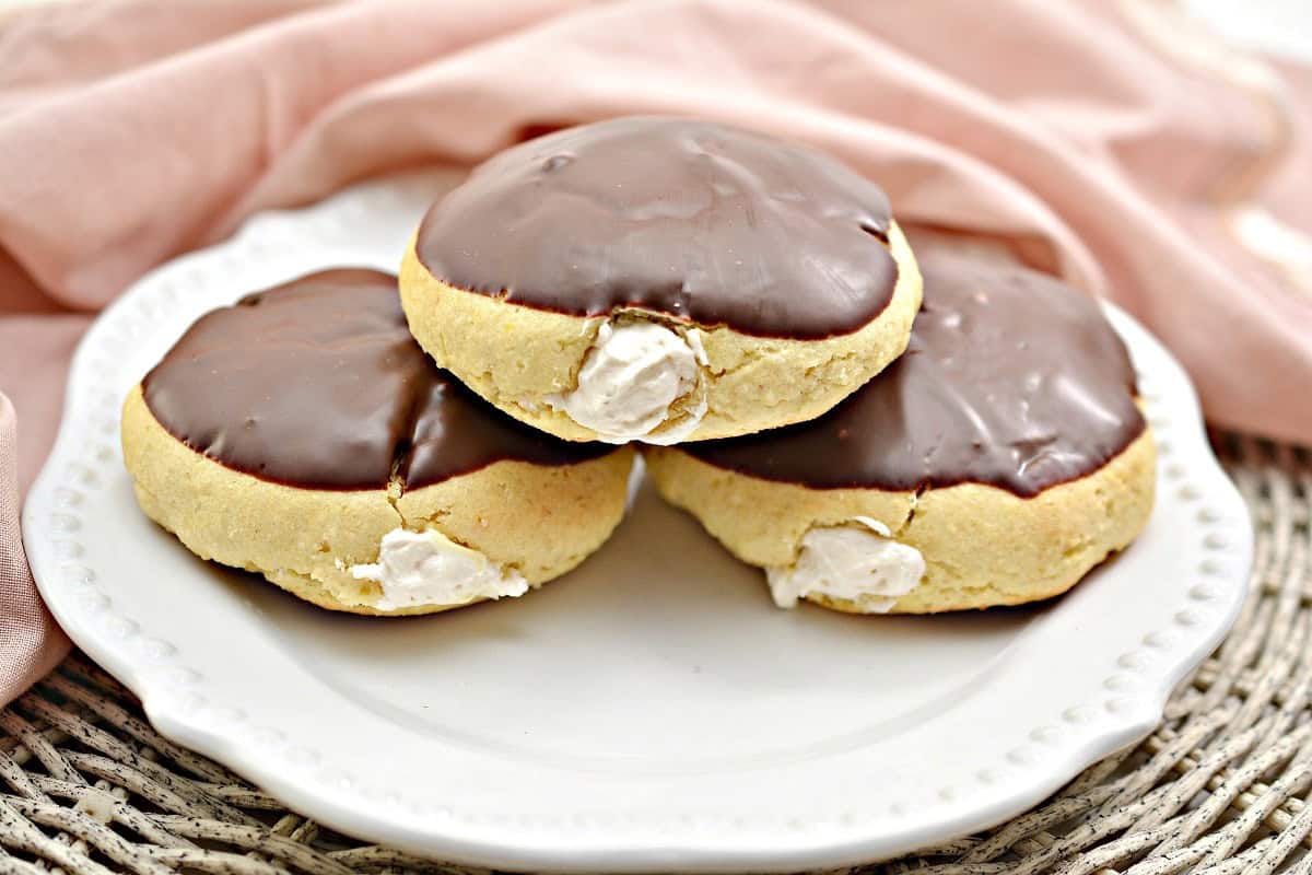 Three chocolate covered cookies on a white plate.