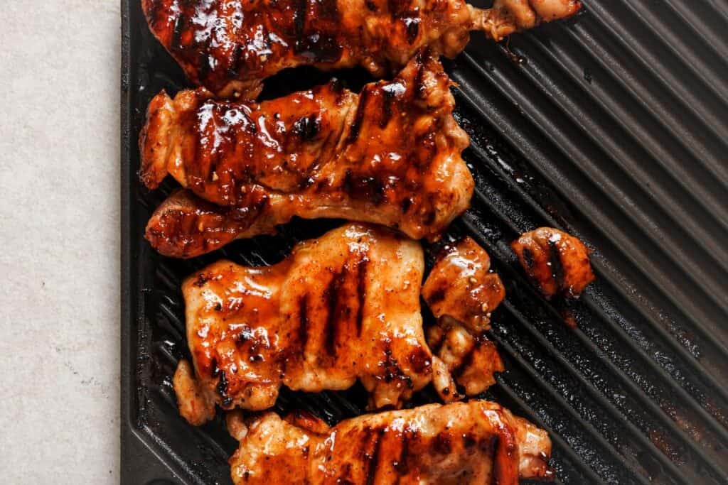 Grilled pieces of marinated meat with a glazed finish on a ribbed grill pan.