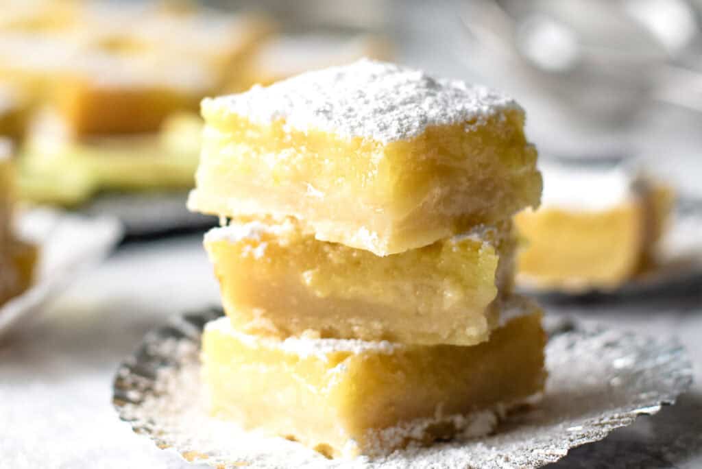 A stack of three lemon bars on a plate.