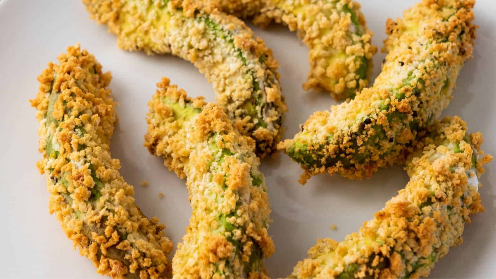 Close-up of crispy, breaded Air Fryer Avocado Fries on a white plate.