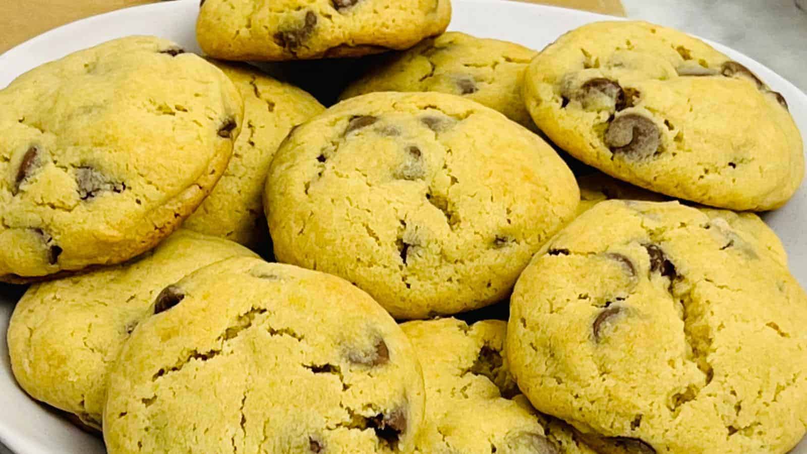 A close-up of a plate, filled with multiple golden-brown chocolate chip cookies.